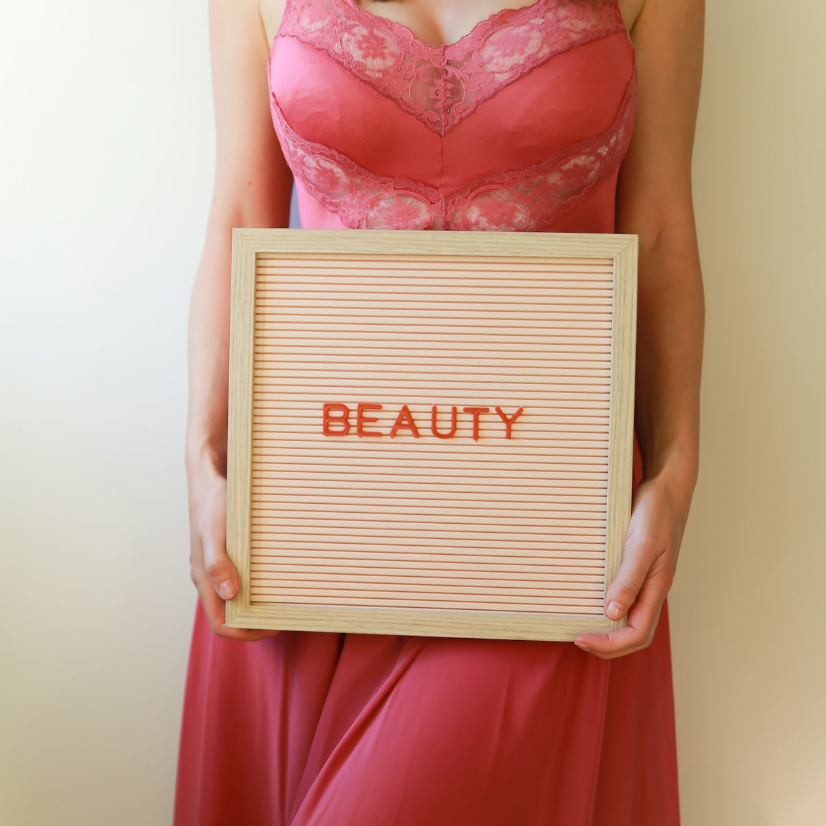 A woman in pink holds a sign that says beauty.